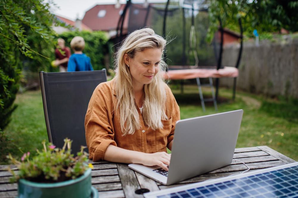 Woman working on laptop in backyard