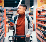 Man holding phone and pushing a shopping cart in a grocery store
