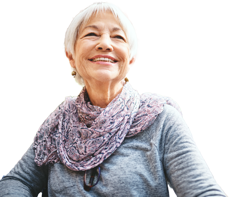 Une femme âgée aux cheveux courts portant une écharpe colorée à motifs qui regarde vers le haut avec un grand sourire.