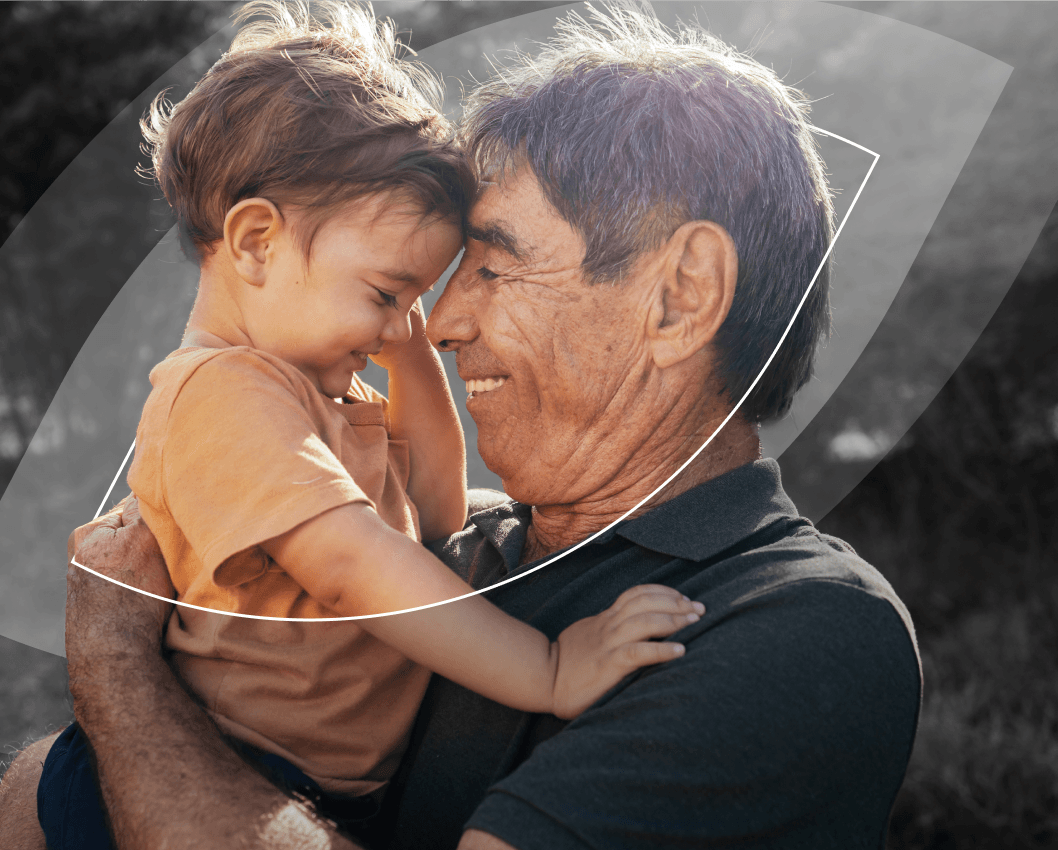 Grandparent holding grandchild and smiling at each other.